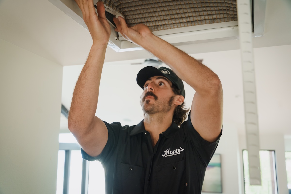 Monty's team member replacing an air filter inside a home