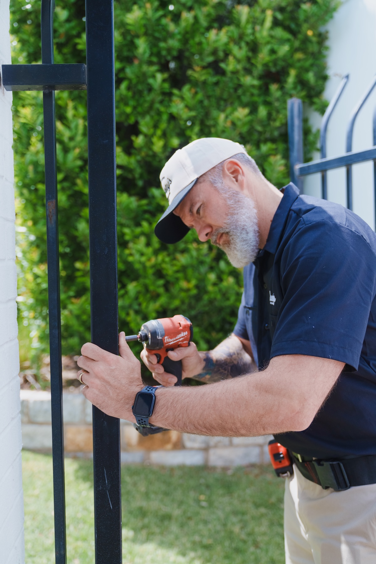 Monty's team member fastening an outdoor metal gate with a drill